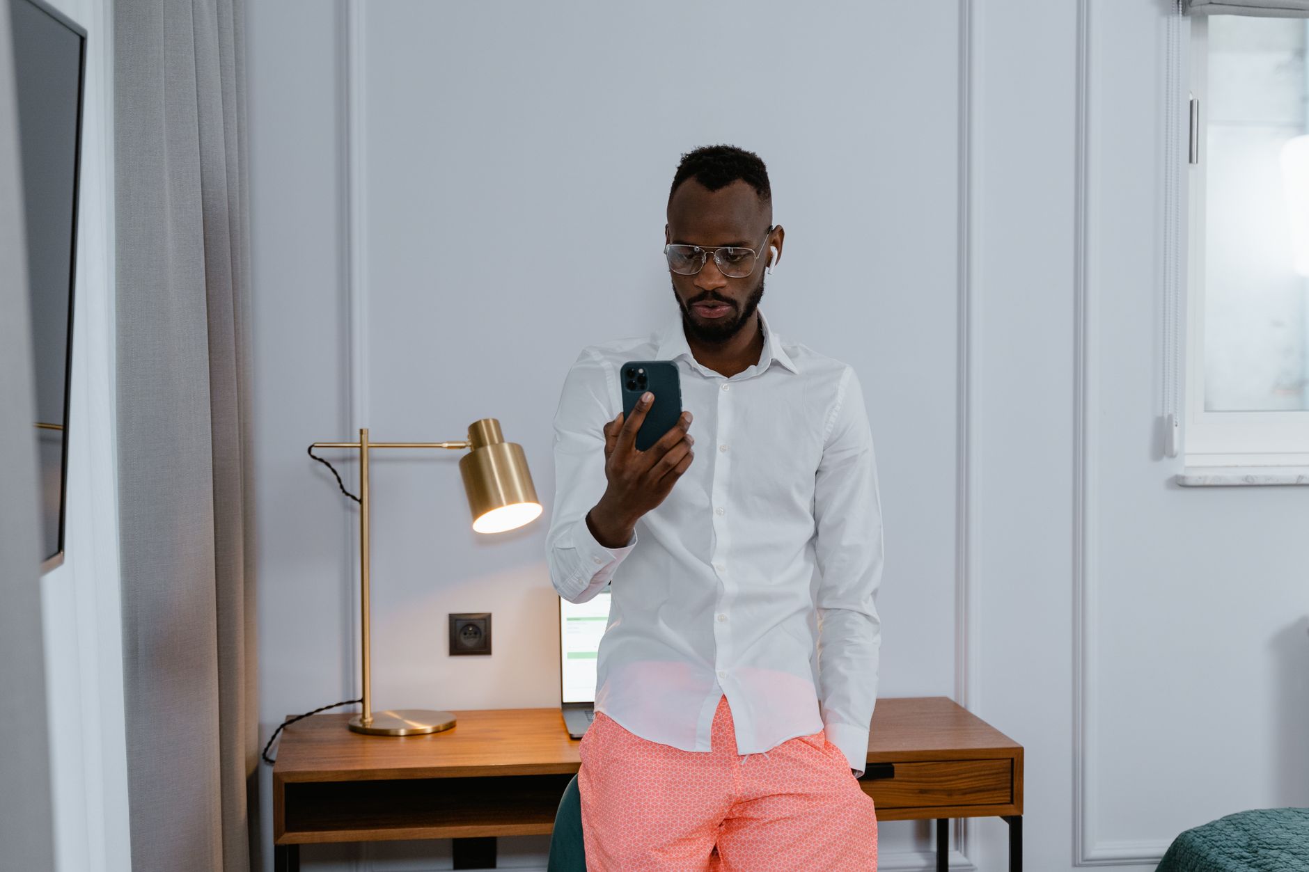 Man in a smartly furnished room checking his phone, illustrating record host earnings for short-let owners