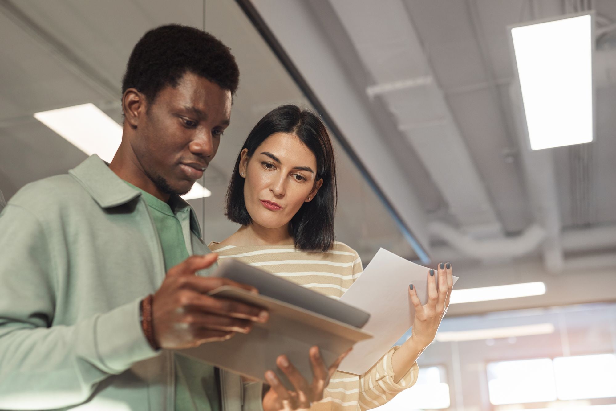 Two business colleagues reviewing documents and a tablet in an office, illustrating CRM for small business