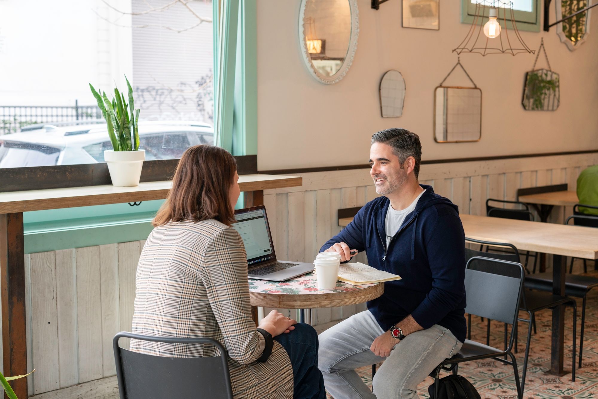 Two people meeting over coffee and laptop in a cafe, illustrating Social Investment Scotland funding