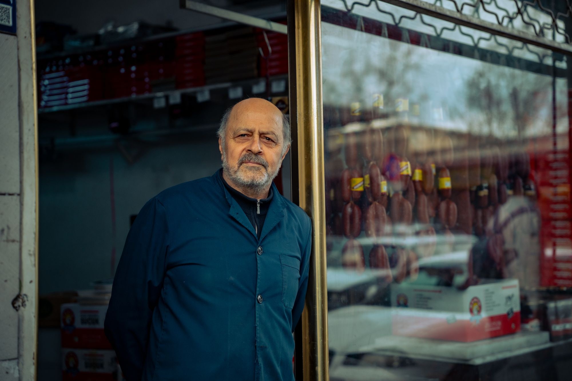 Small business shop owner standing in the doorway of his deli storefront