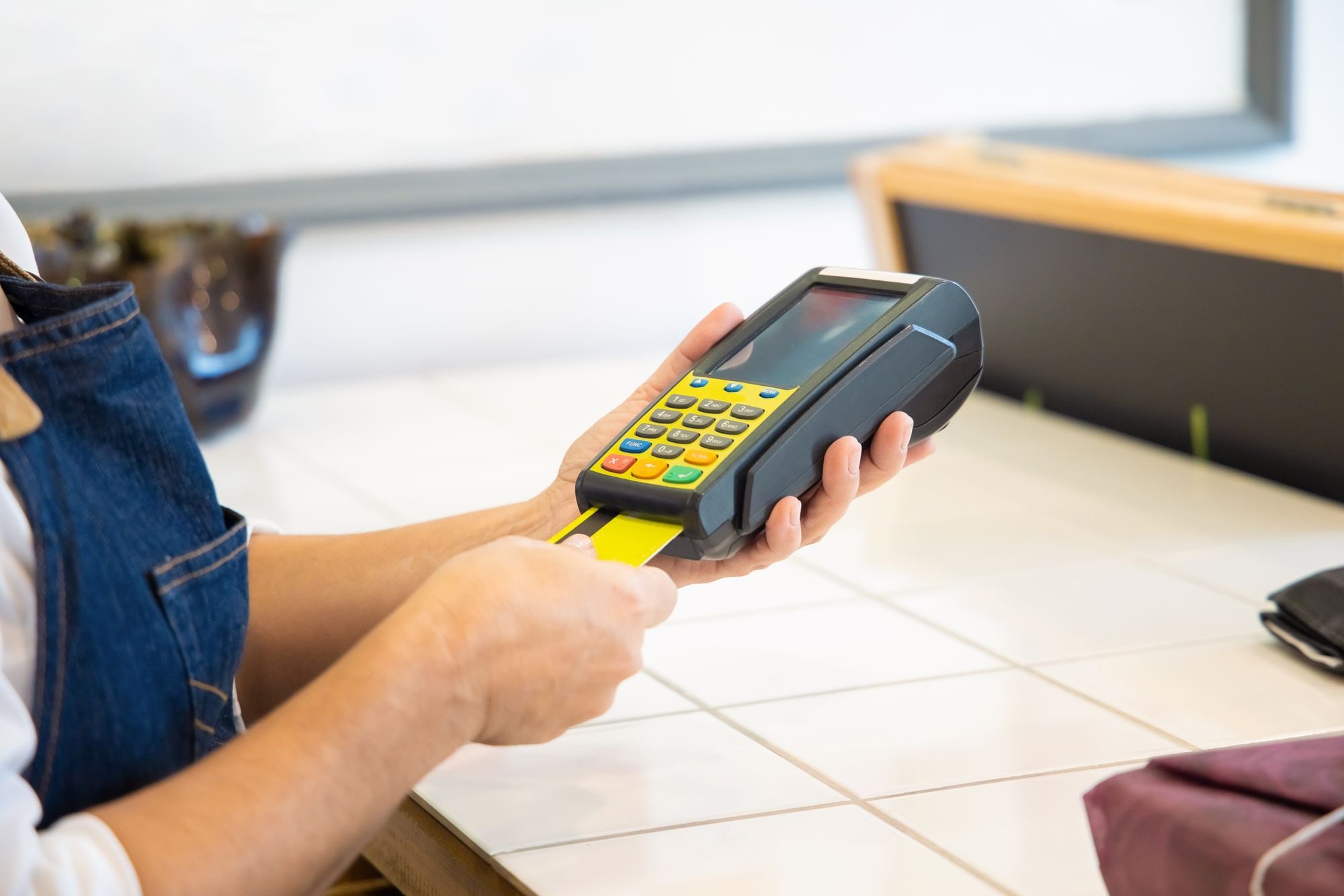 Customer inserting a yellow card into a handheld payment terminal, illustrating card payment fees UK small businesses pay