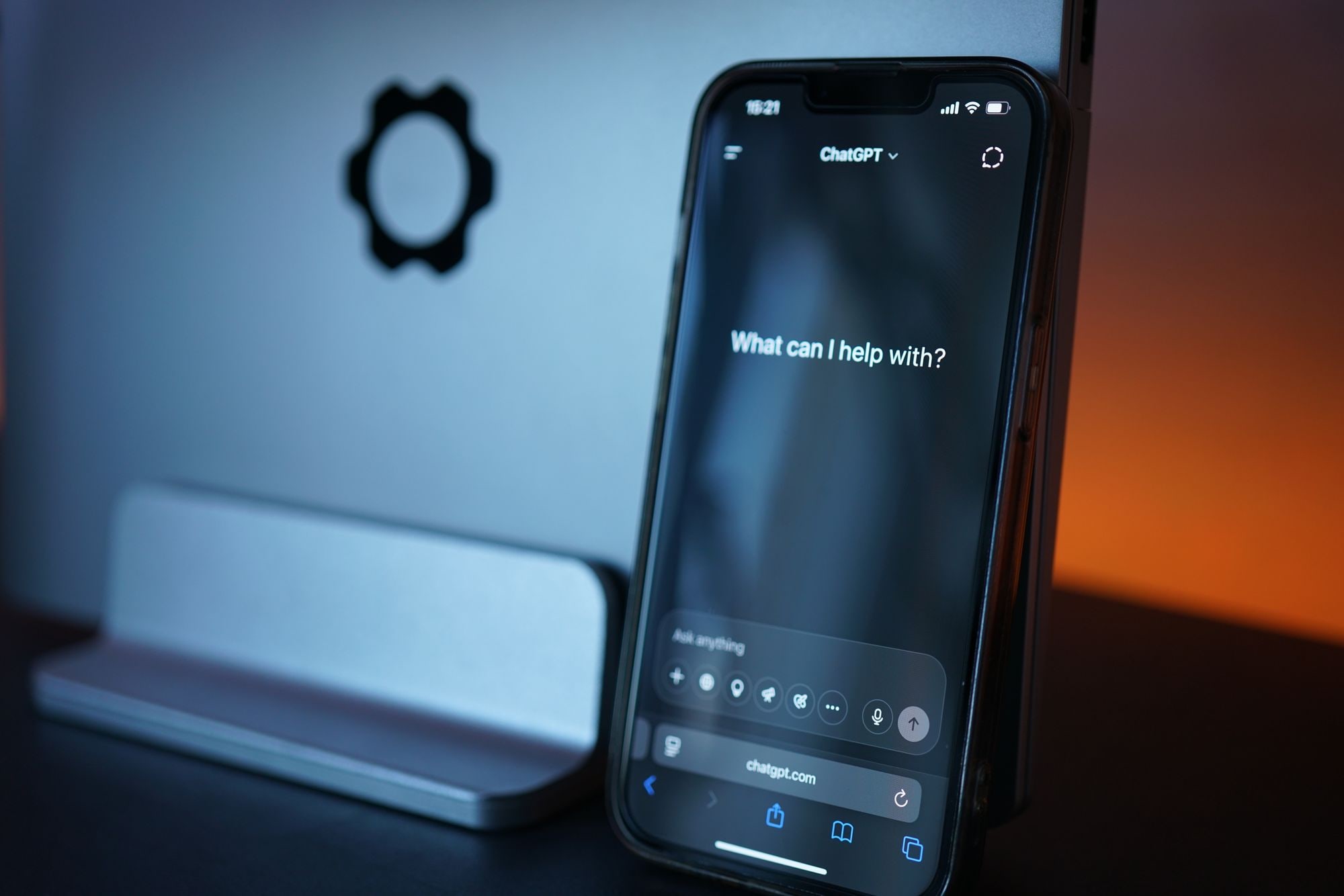 Smartphone displaying the ChatGPT AI assistant interface asking 'What can I help with?' beside an OpenAI logo