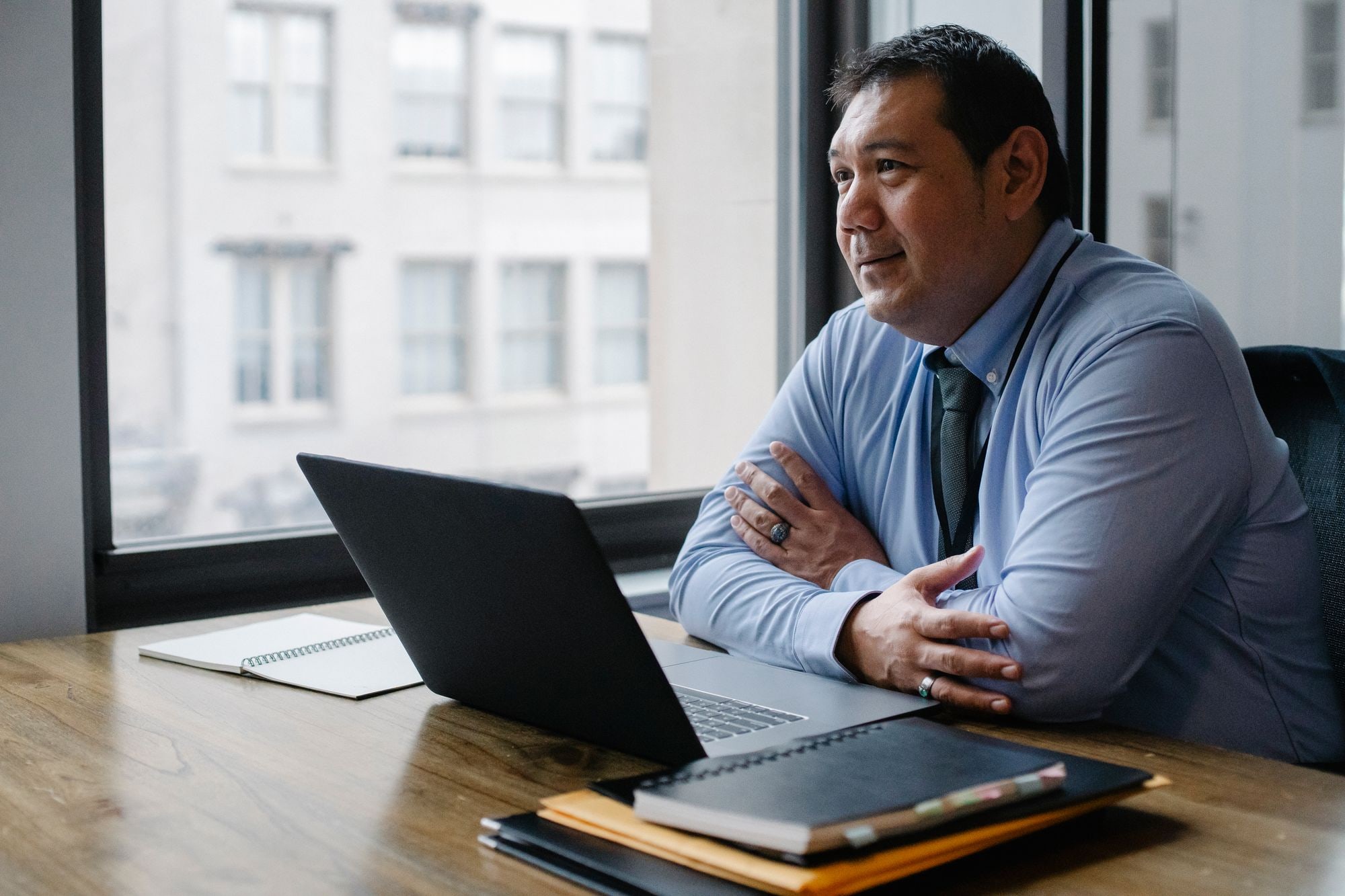 Businessman in blue shirt and tie at office desk with laptop, considering Companies House identity verification requirements
