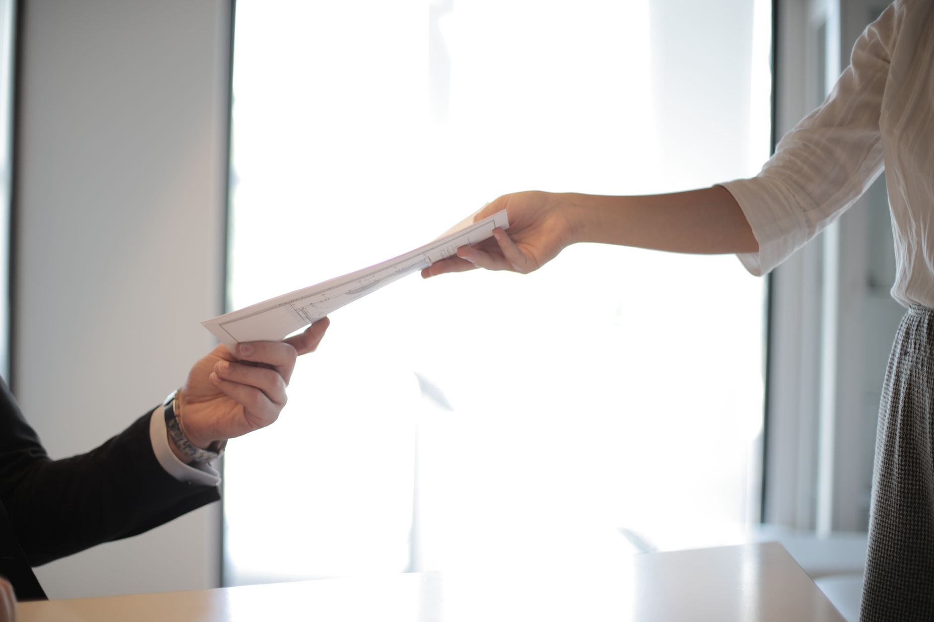 Person handing employment documents to another in an office, illustrating day-one employment rights