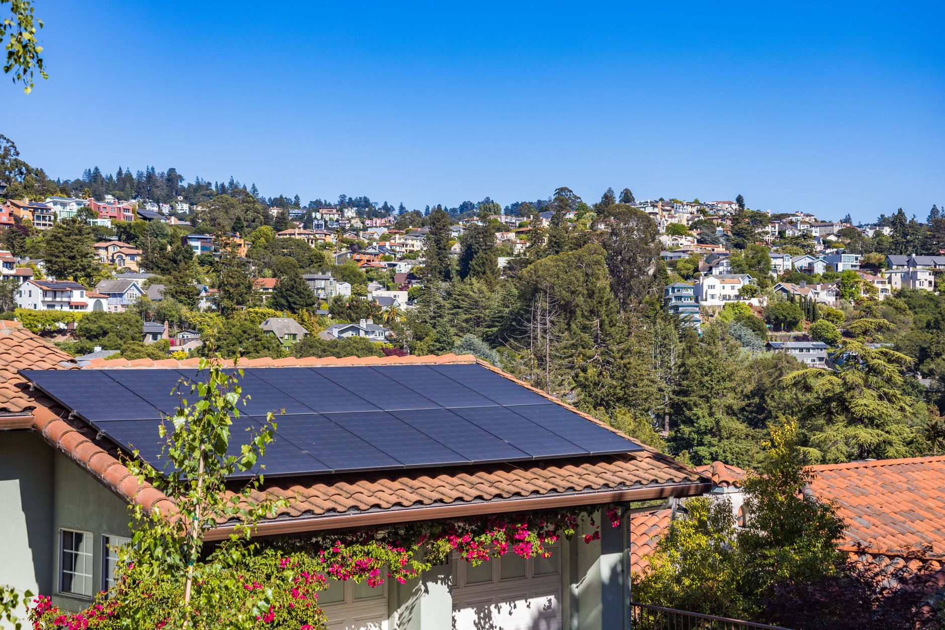 Rooftop solar panels on a house overlooking hillside homes, illustrating solar power to cut small business energy bills