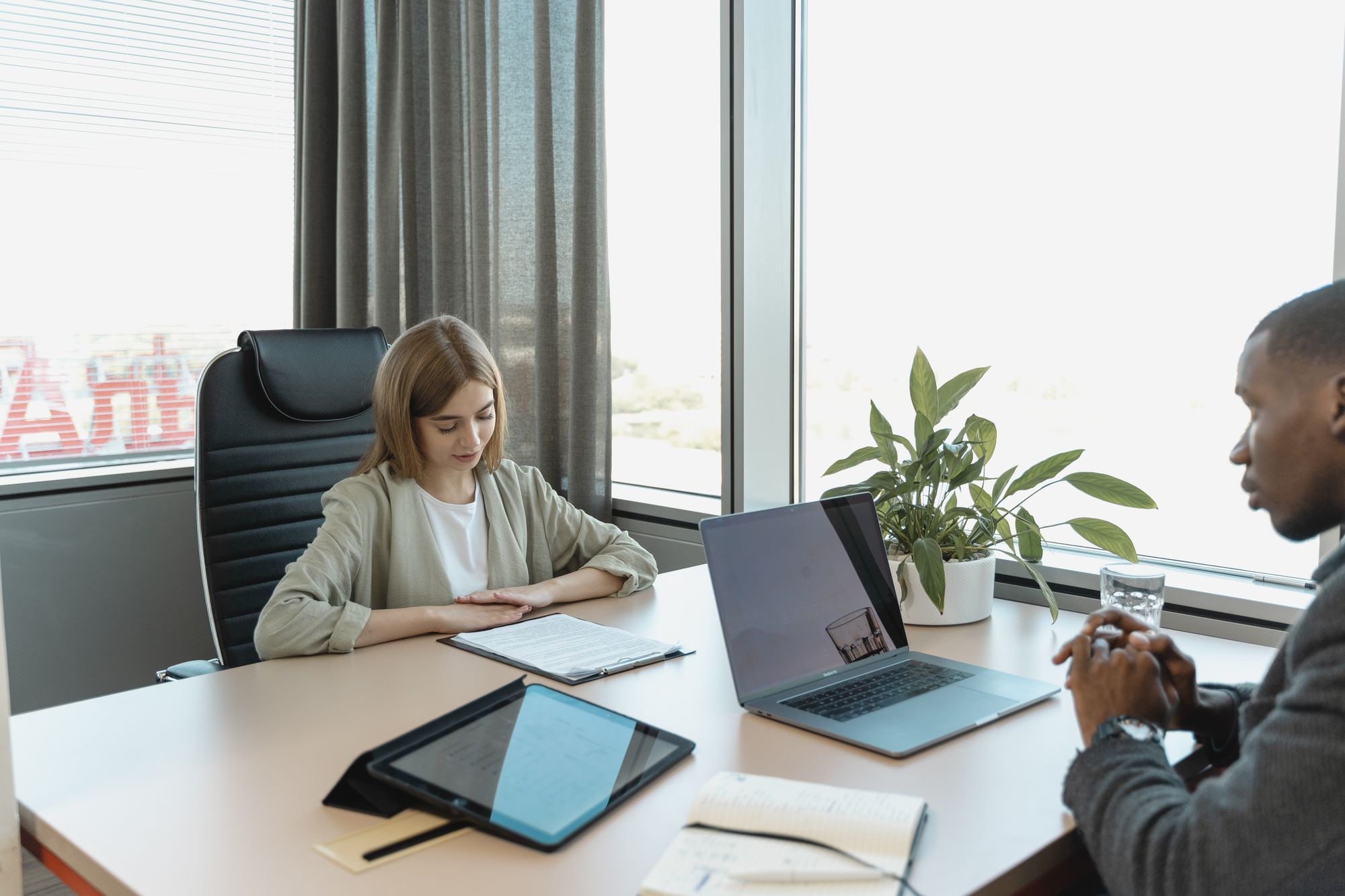 Two people in an office meeting reviewing documents and a laptop, illustrating hiring your first employee UK