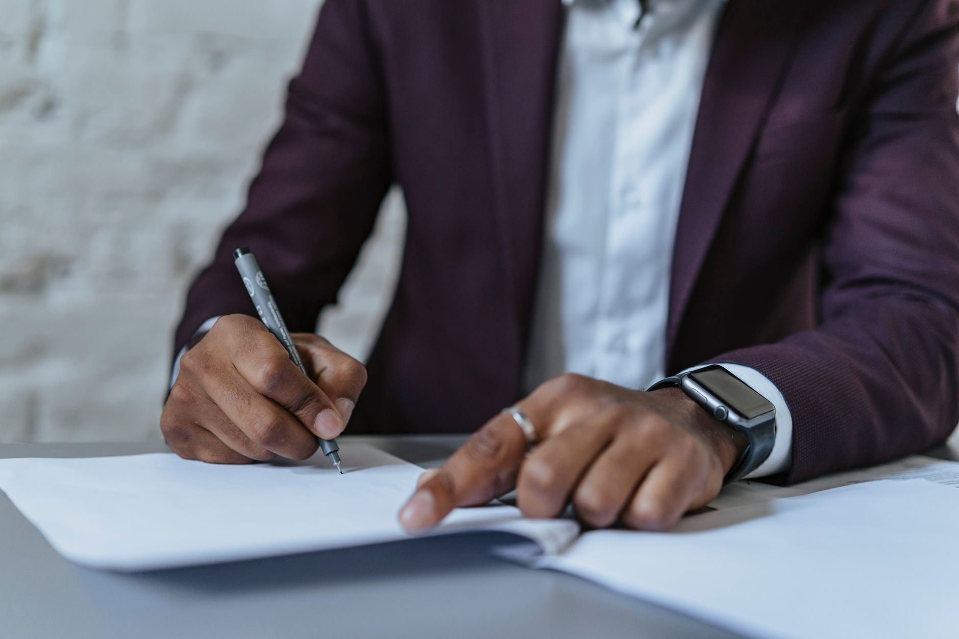 Businessman in suit signing paperwork at desk illustrating how to buy a small business UK