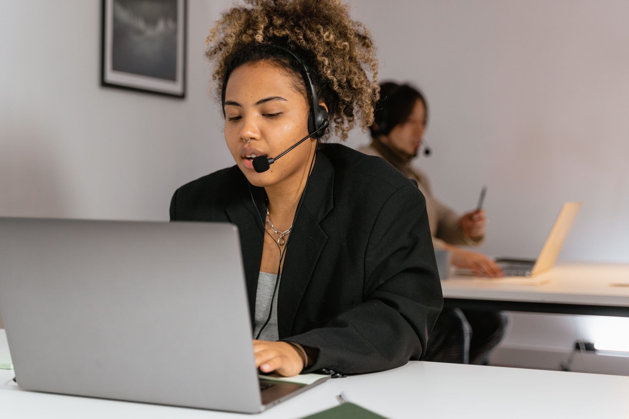 Customer service agent wearing a headset working on a laptop in a small business call centre office.