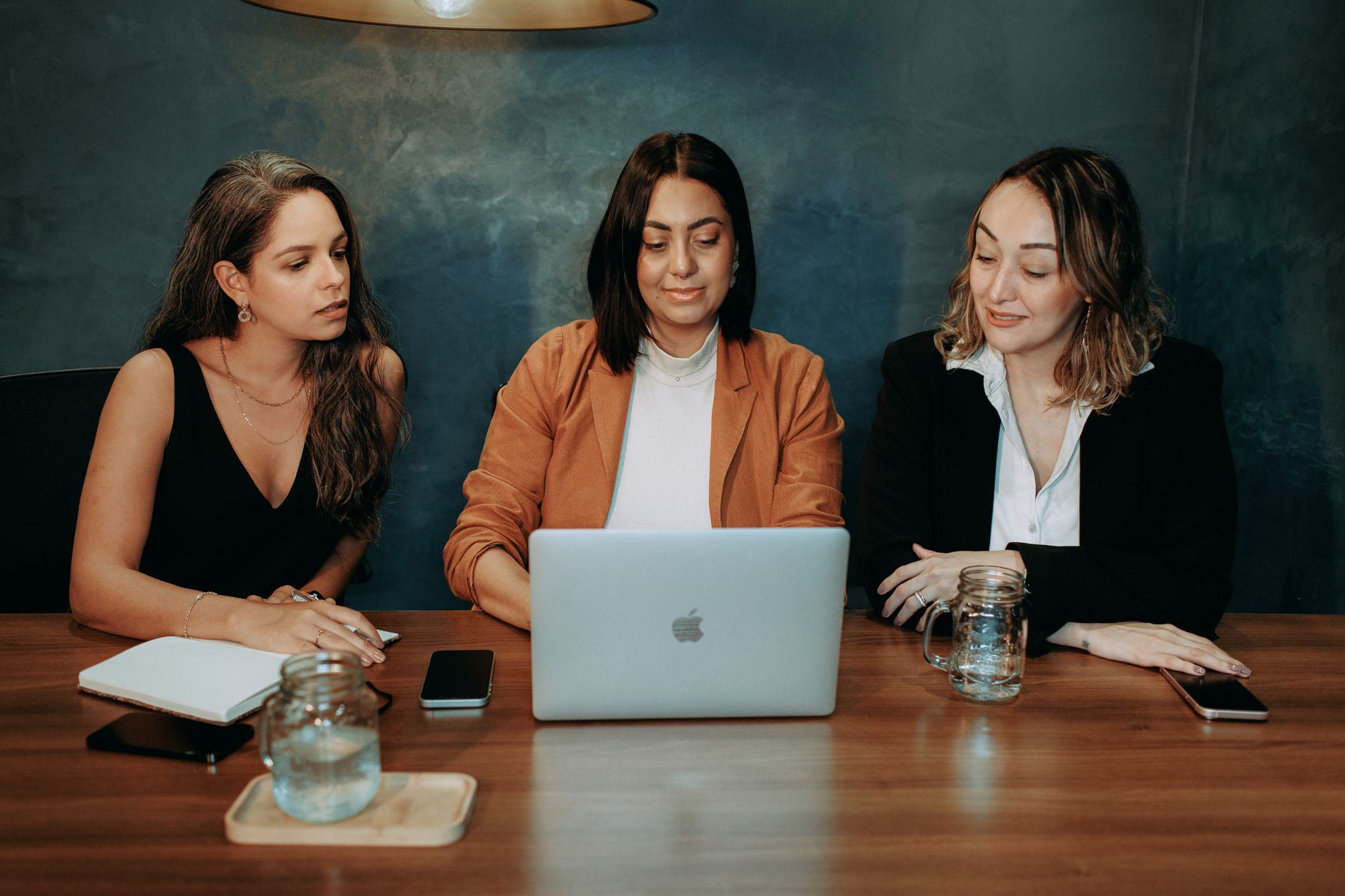 Three women entrepreneurs working together at a laptop, illustrating Innovate UK backs 100 women founders