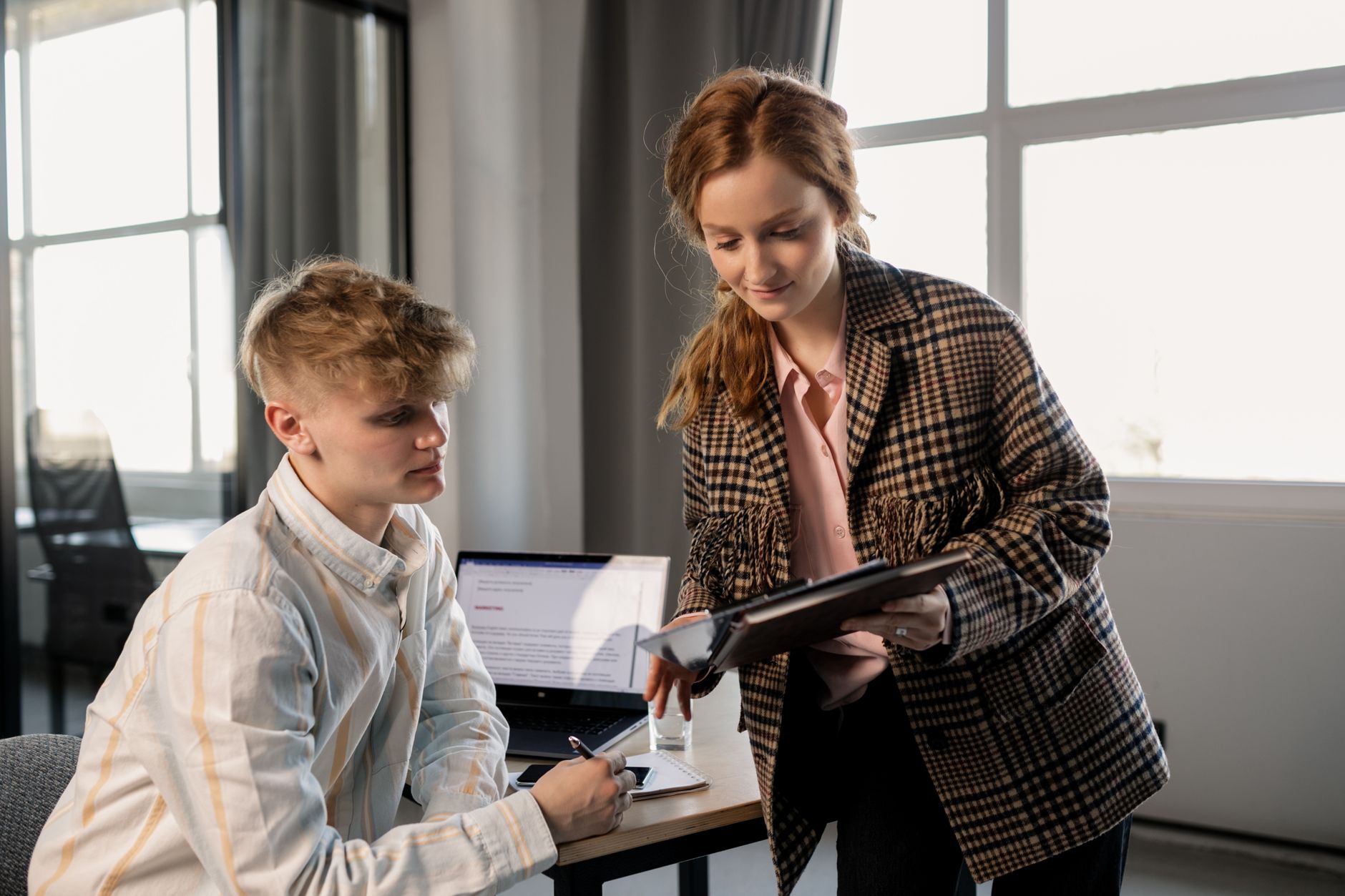 Two young colleagues reviewing paperwork in an office, illustrating the proposed National Insurance cut for under-25s