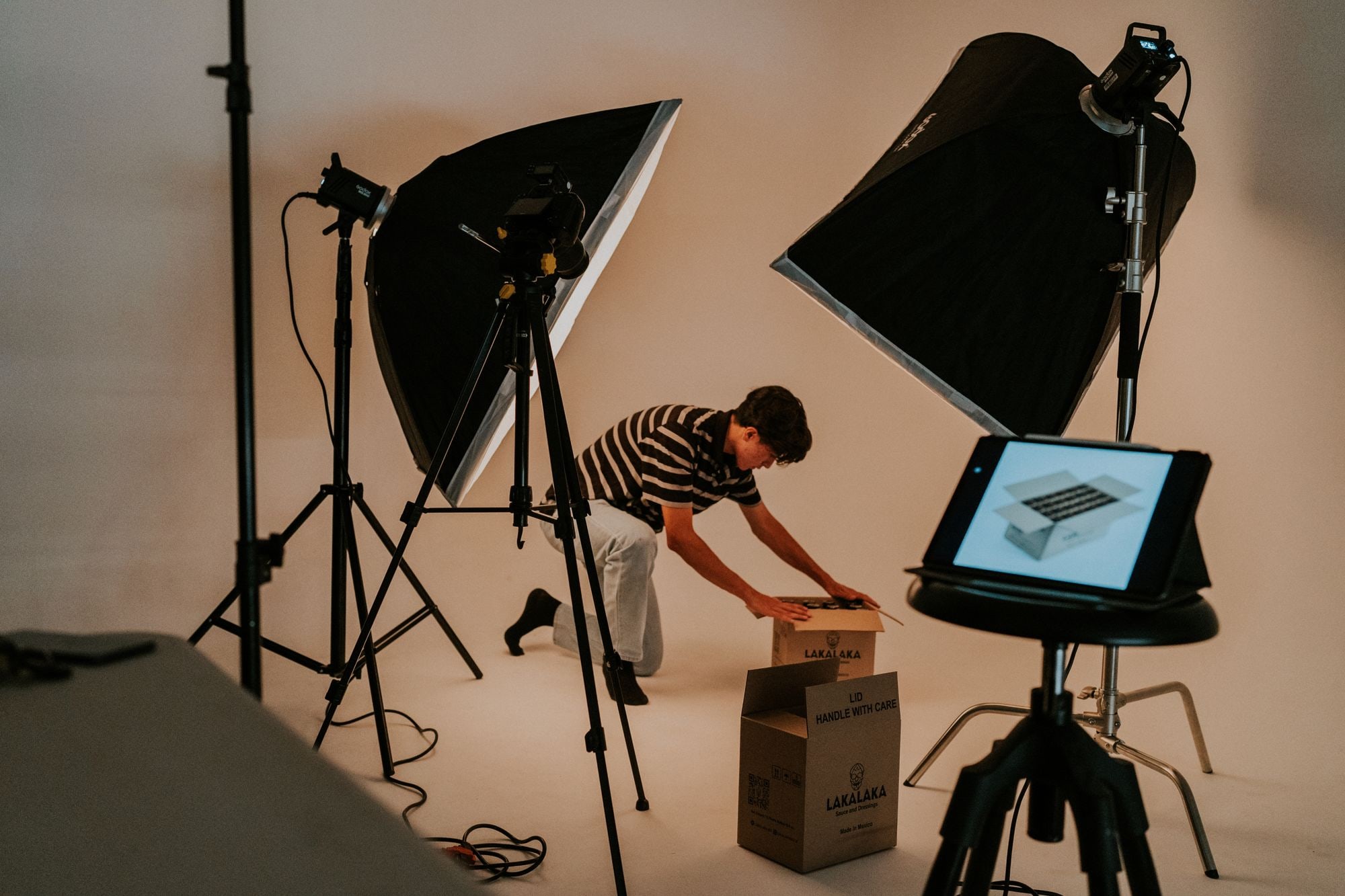 Small business seller photographing packaged products in a lit studio setup for online shop listings