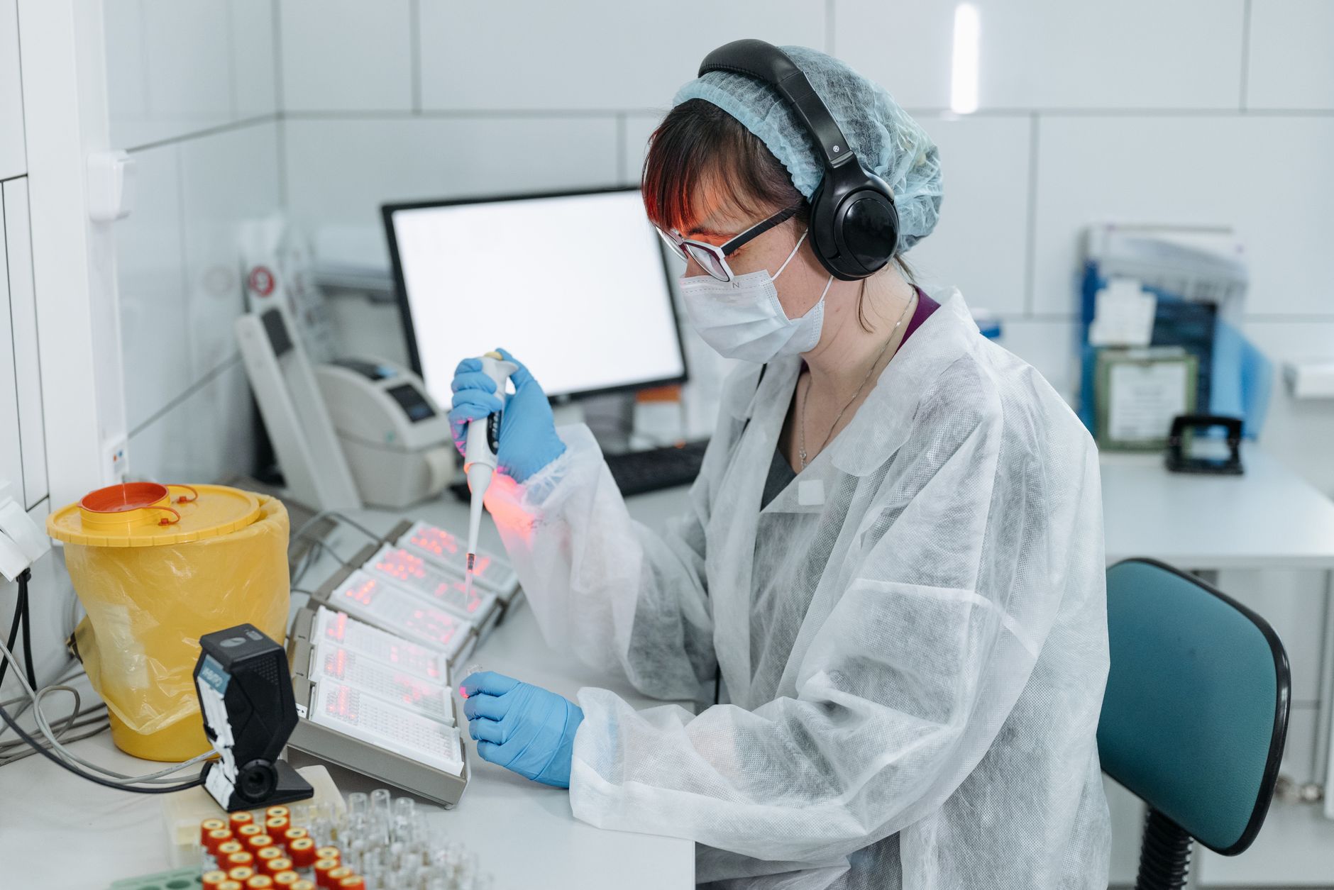 Lab technician in PPE pipetting samples, illustrating personalised lung cancer vaccine DNA research