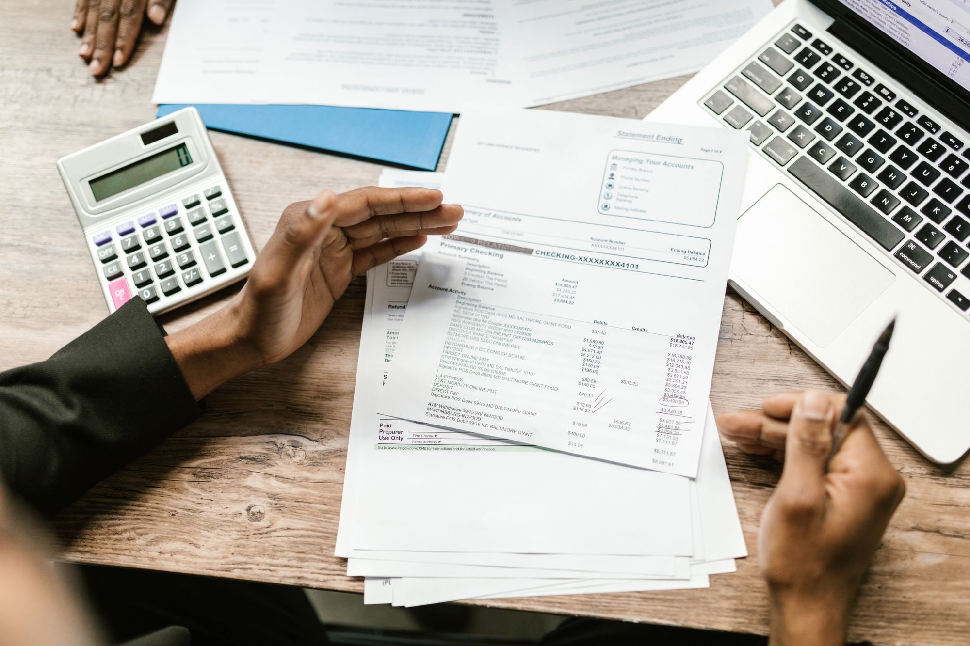 Person reviewing bank statement with calculator and laptop, illustrating VAT registration UK for small businesses