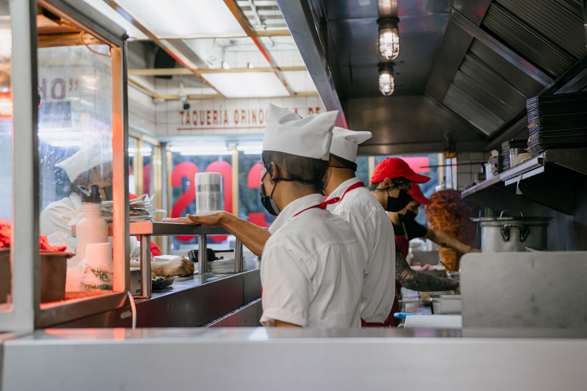 Masked chefs working in a busy taqueria kitchen, illustrating zero hours contract reforms in hospitality